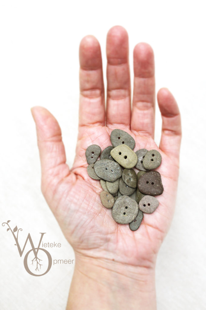 hand filled with various handmade riverstone buttons